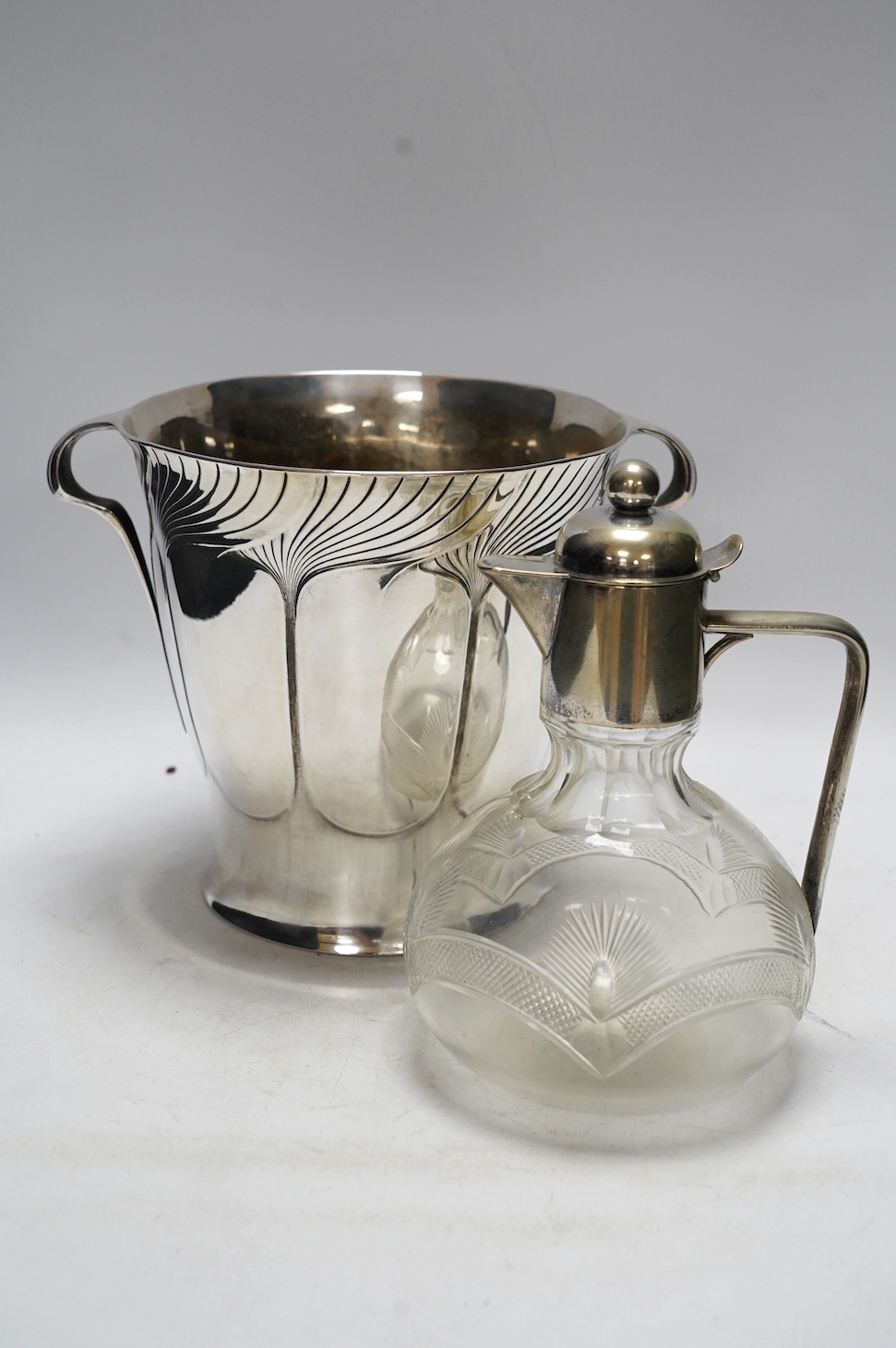 An Art Nouveau Orivit polished pewter wine cooler, c.1905, impressed model number 2447, 20cm high, and an early 20th century WMF electroplate mounted cut glass claret jug, 21.5cm high (2). Condition - fair to good